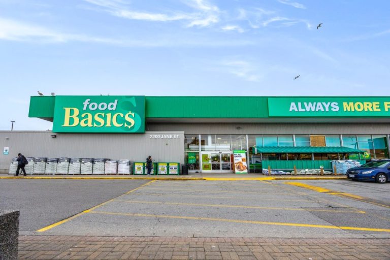 Food Basics store front at 2200 Jane St., showcasing its green signage and promotional banners. Shoppers walk by with bags in hand.